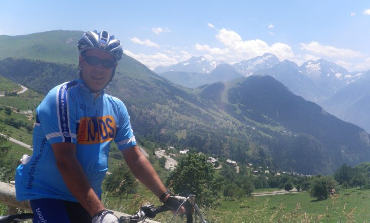 alain on his bike with mountains in the background on a sunny day