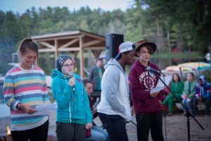 campers singing with volunteer at campfire next to the lake at ooch muskoka