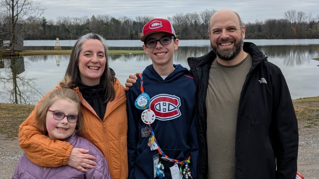 rosie and her family at camp in front of the lake on a cool day