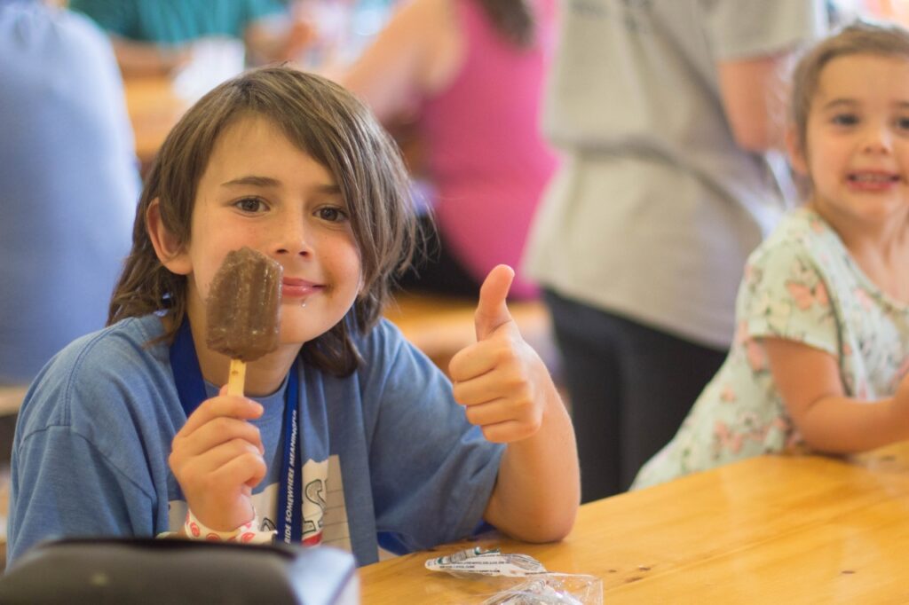 camper with fudgsicle giving a thumbs up
