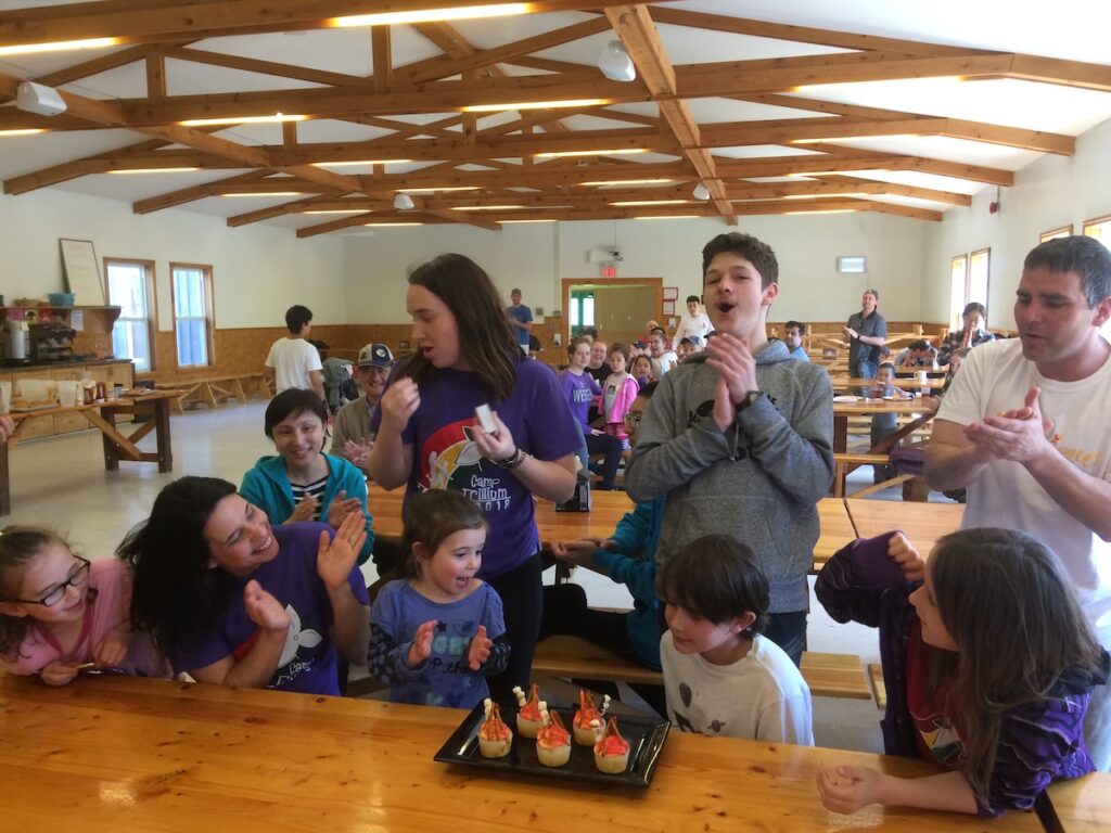 family in the dining hall at camp celebrating a birthday with cupcakes
