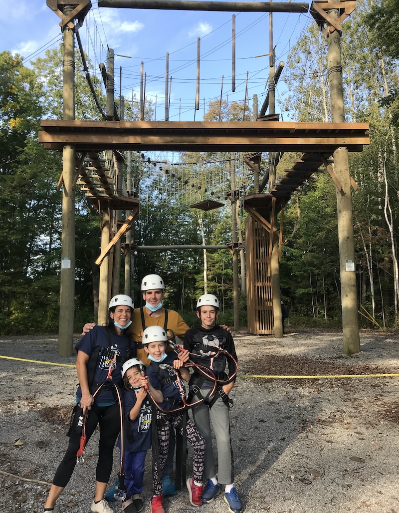 family in climbing gear with ropes course in background