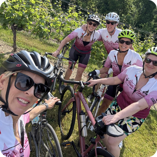 tour_Blog Image_feature group of tour riders outside in the sunshine surrounded by vineyard and trees