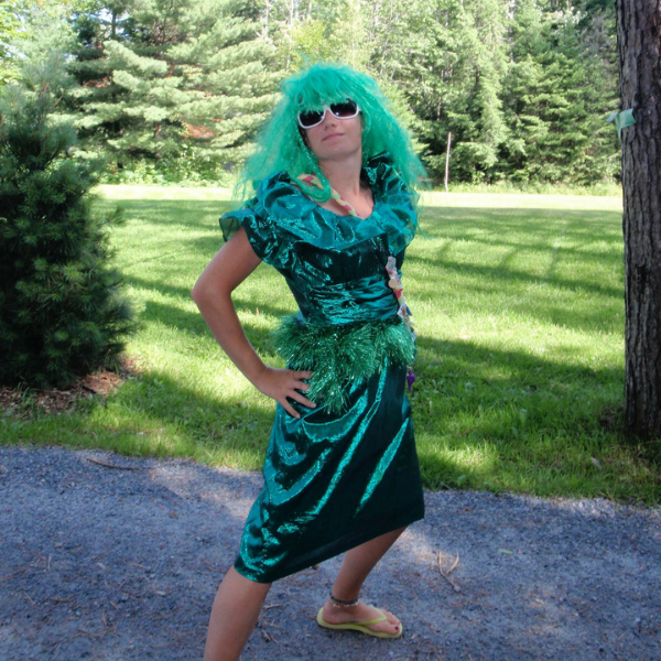 counsellor in costume outside at camp on a sunny day with trees and nature in the background