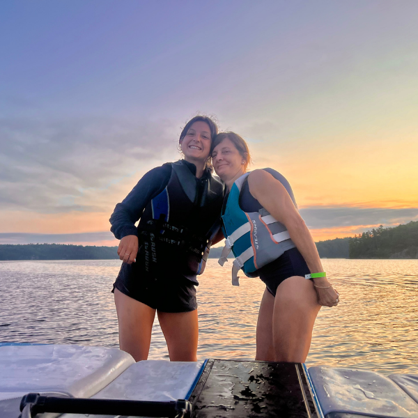 counsellors standing on the back of a boat with lake and trees in background