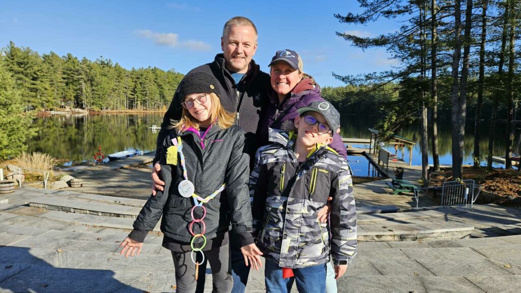 nash family at camp on a sunny fall day with lake and trees in the background