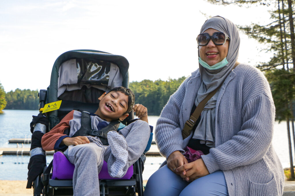 nidra and her son smiling in front of the lake at camp