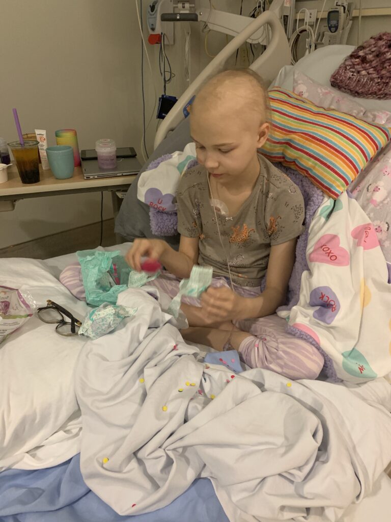 emma in a hospital bed with toys