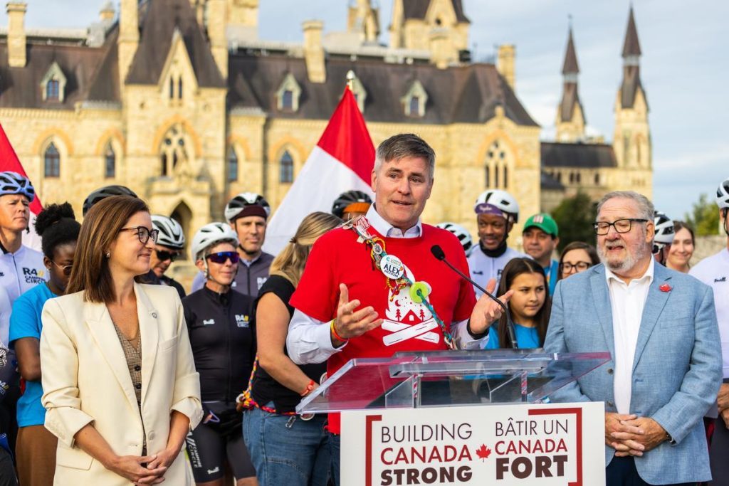 alex with riders, families and politicians with parliament hill in the background