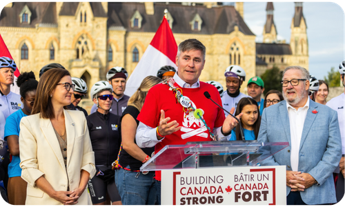 alex with riders, families and politicians with parliament hill in the background