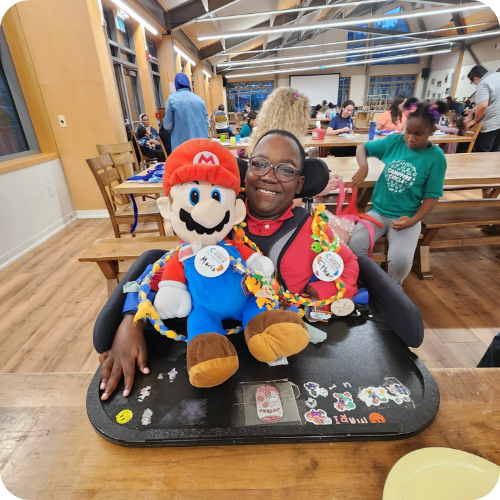 Blog Image – Ethan ethan with mario doll in the cafeteria at camp