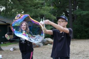 Two campers blowing giant bubbles outside at CAMPFIRE CIRCLE Muskoka