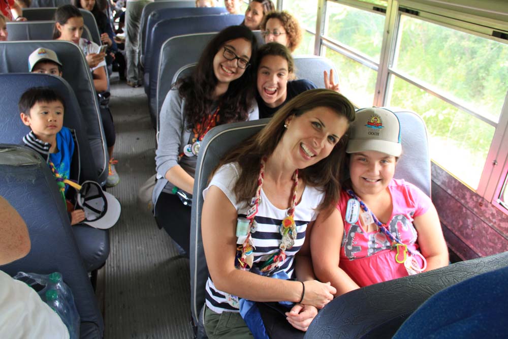 volunteer sitting with campers on the bus