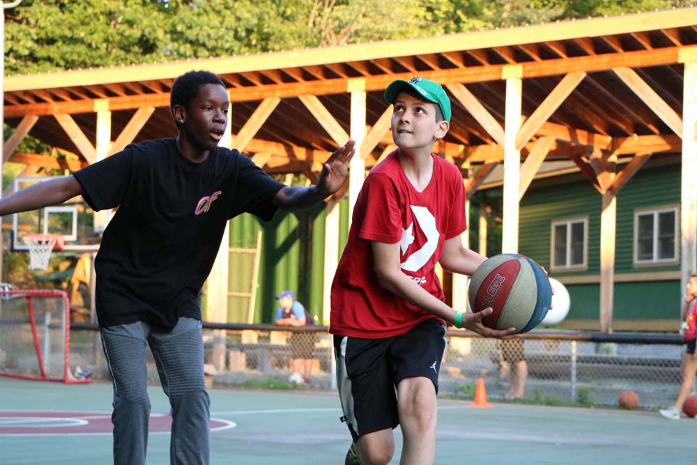 Two campers playing basketball outside