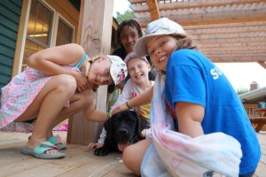 campers hanging out with dog on the porch at camp