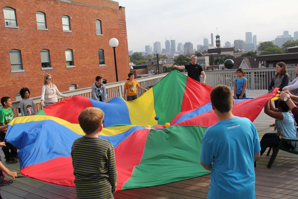 Campers playing with parachute on rooftop deck at CAMPFIRE CIRCLE Downtown