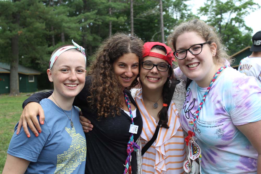 Four campers smiling and posing for a picture outside