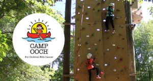 campers climbing rock wall in safety gear