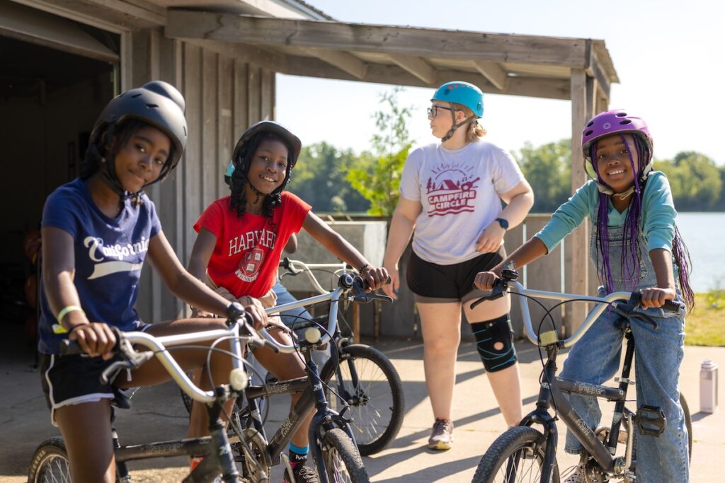volunteer with campers on bikes at camp