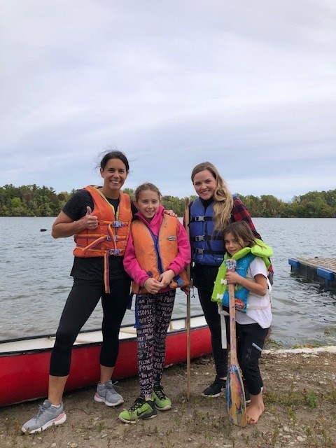 family at the edge of the lake, in front of canoe