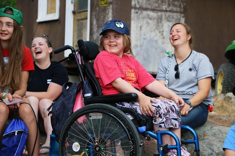 Carissa in wheelchair laughing with other campers