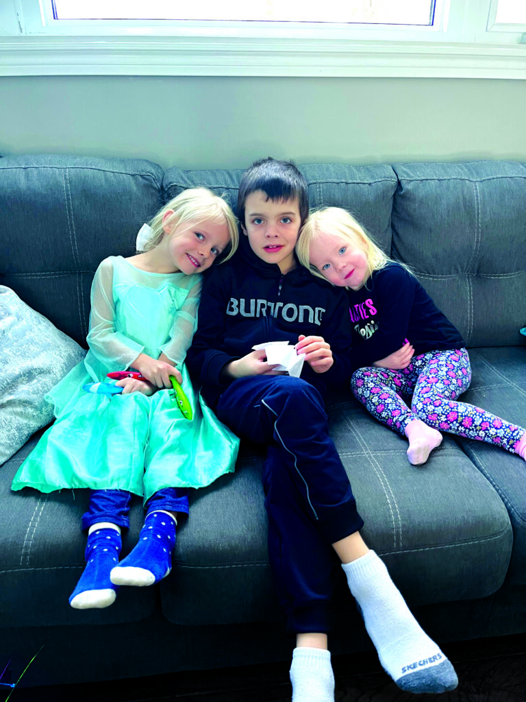joel sitting with his sisters on a couch