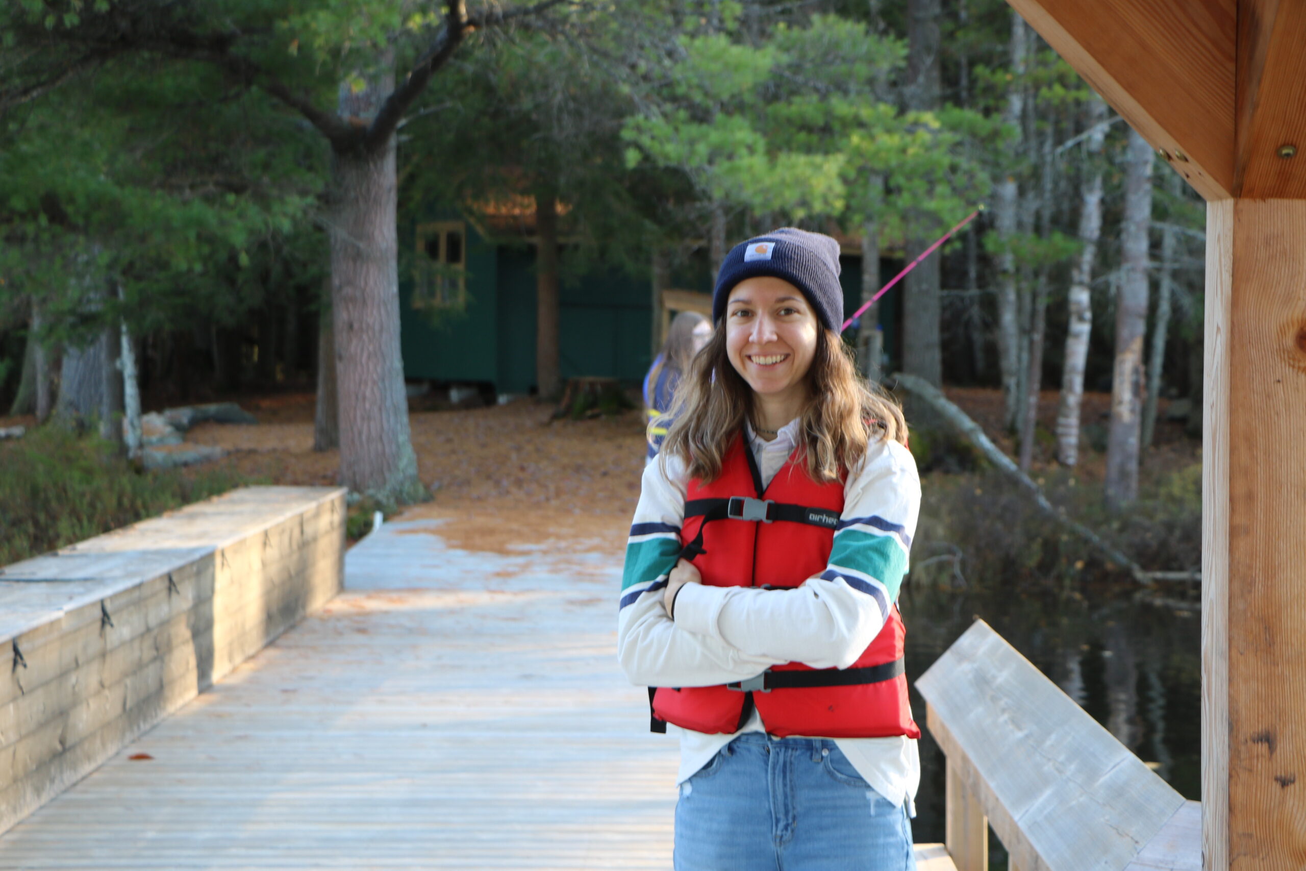 volunteer standing on dock at camp wearing life jacket