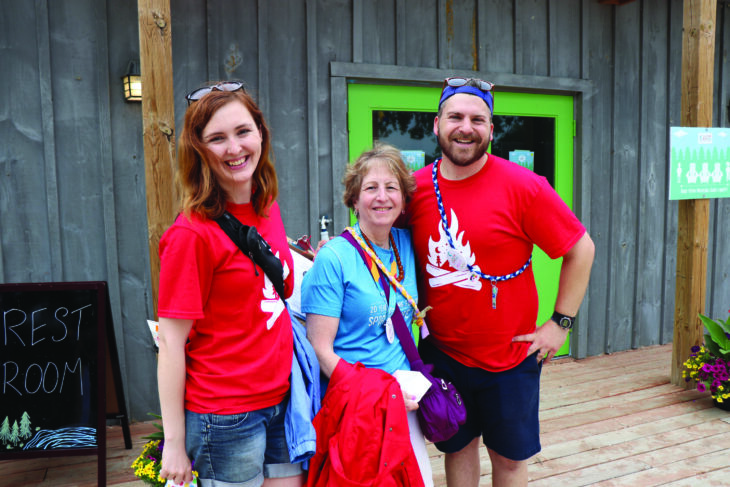 staff members posing for photo with volunteer outside cabin at camp