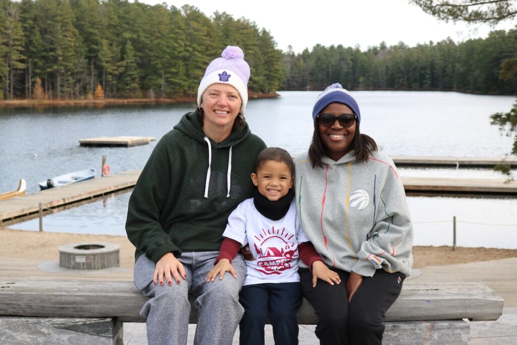 carter and his parents sitting at camp with lake in the background