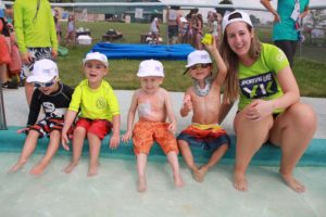 volunteer with campers soaking feet in kiddie pool at day camp