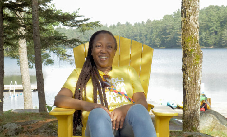 judy sitting on a camp chair with lake in the background