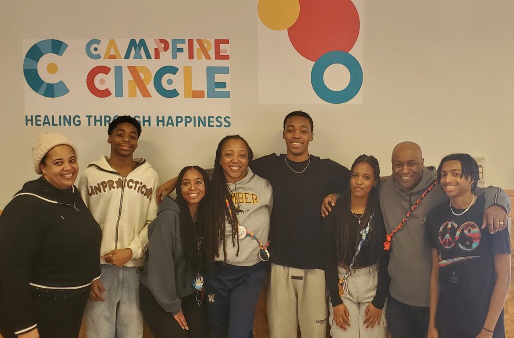 family standing under campfire circle sign
