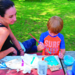 mother and son painting on a picnic table