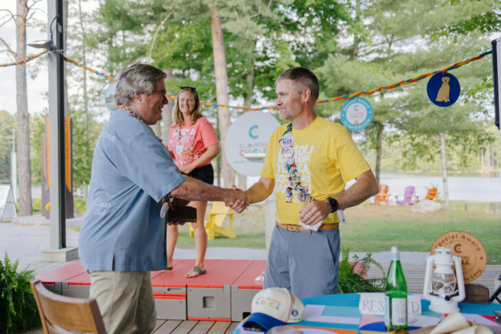 Stu Lang, philanthropist, shakes hands with Alex Robertson, CEO of Campfire Circle
