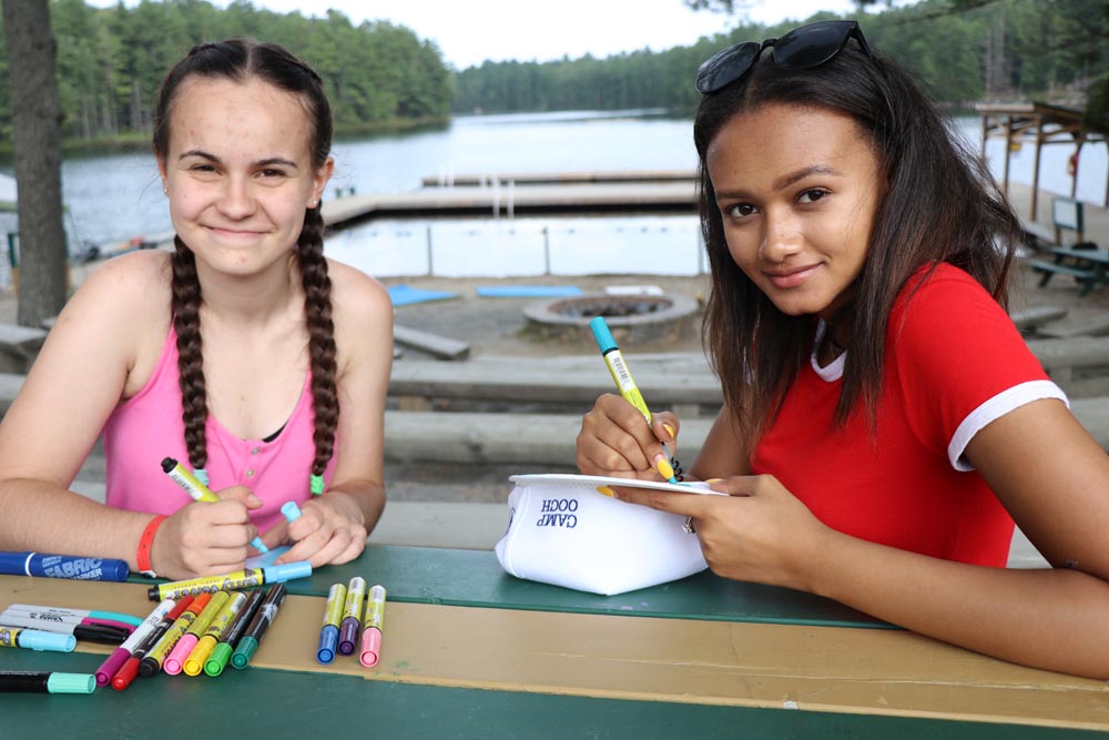 Larissa and friend drawing on a bench overlooking the lake at CAMPFIRE CIRCLE Muskoka