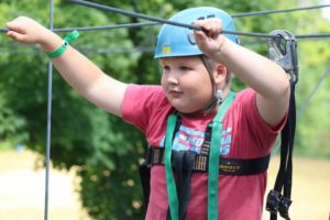 Close up shot of Oscar with helmet on climbing the high ropes course at CAMPFIRE CIRCLE Muskoka
