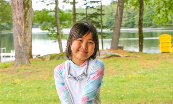 radda in swimsuit with lake and trees in background