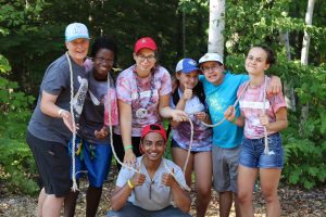 group of teenagers posing for a picture outside at camp