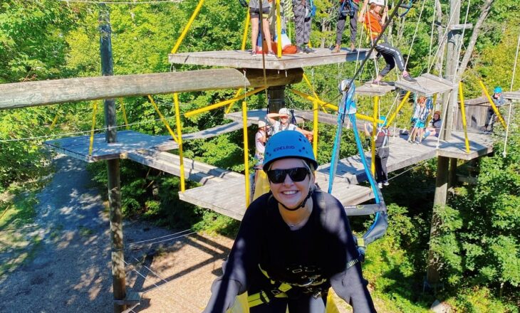 volunteer in safety gear on the high ropes course