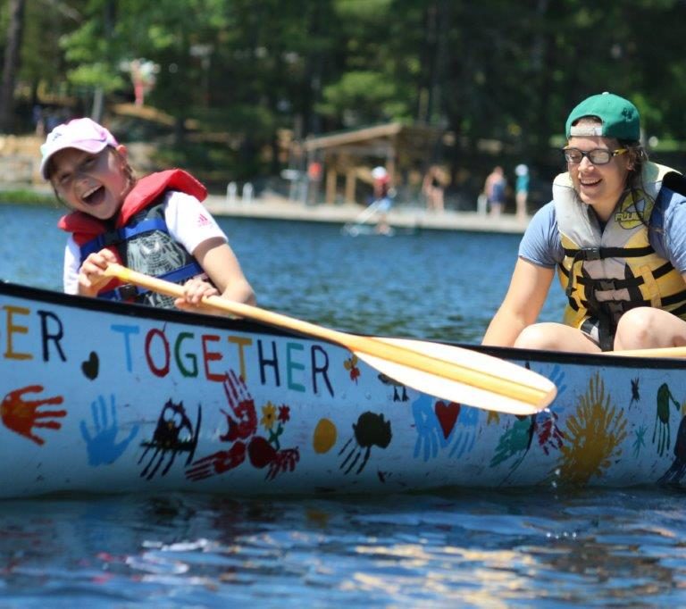 campers in a canoe on the water, laughing