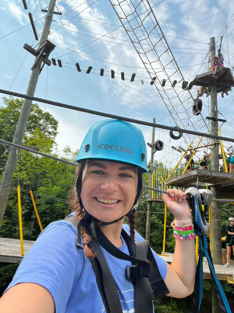 volunteer in safety gear at the high ropes course at camp