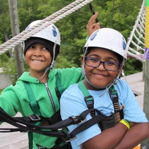 children wearing helmets on high ropes course